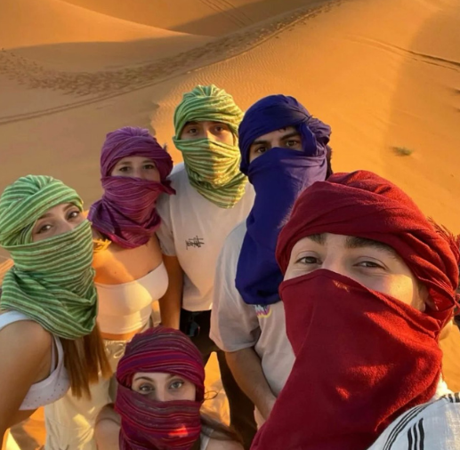 People waiting for sunset in Merzouga, Morocco Tourists enjoying the desert sunset in Merzouga Sunset watchers in Merzouga dunes near Marrakech Travelers observing sunset in Erg Chebbi desert, Morocco